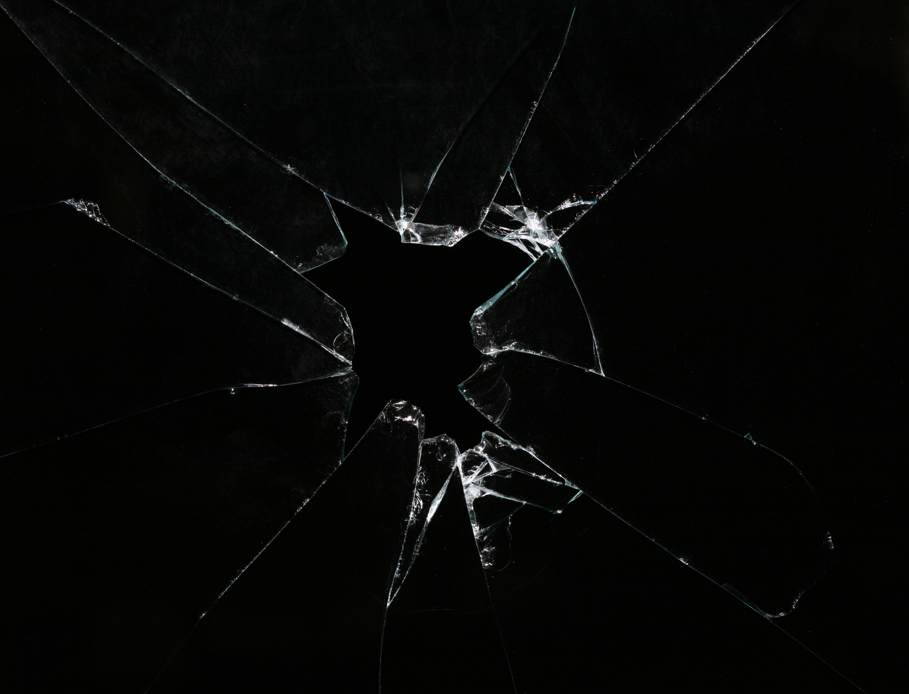 Стеклянные трещины. Разбитое стекло. Трещина на стекле. Треснутое стекло. Трушены на стекле на черном фоне.